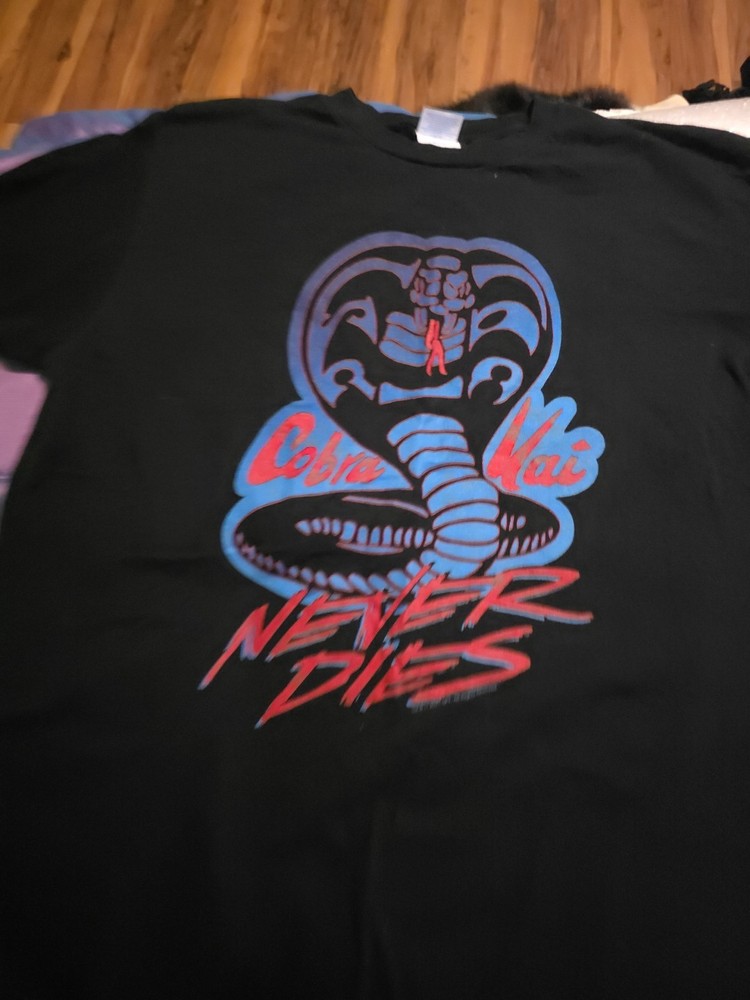 black t-shirt with a blue and red Cobra Kai logo and the text “Cobra Kai…