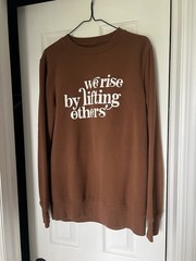 Hand screen printed crew neck “we rise by lifting others” brown medium